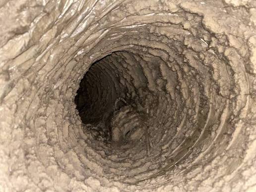 Dirty, dust-caked HVAC ductwork in a Raleigh-area attic with degraded insulation